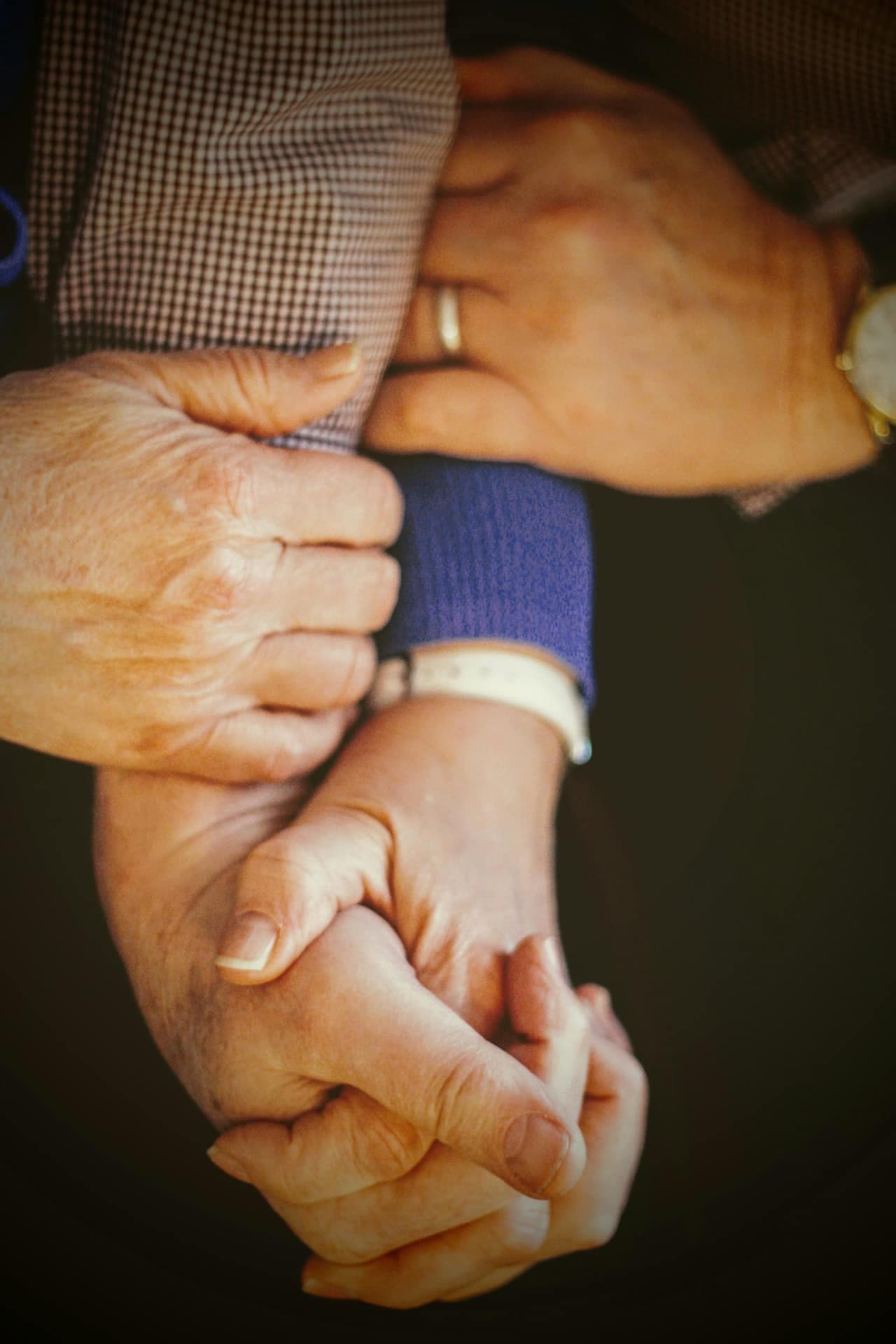 Two pairs of hands clasped together in a supportive gesture