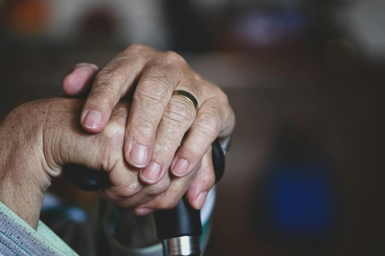Hands resting on a walking cane